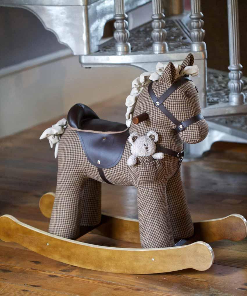 Gyngehest i brunt hanefjedsmønster med brunt læderlook-sadel og en lille bamse på siden